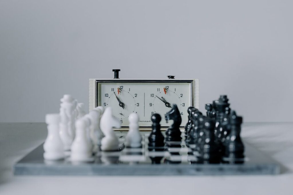Close-up view of a chess match featuring black and white pieces and a chess clock.